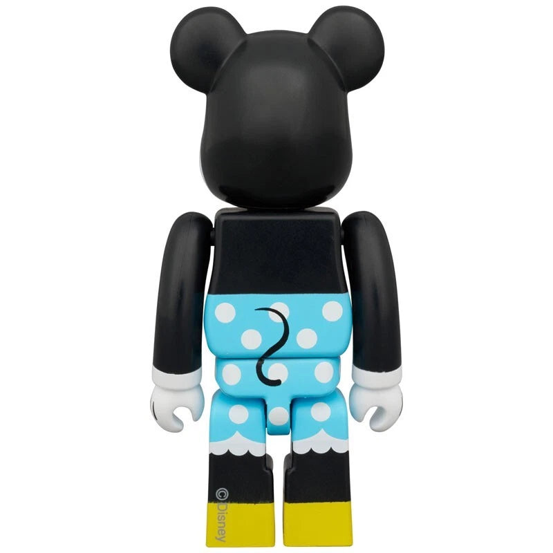 Back of Bearbrick figure dressed as Minnie Mouse with blue polka dot skirt, yellow shoes, and black upper body.