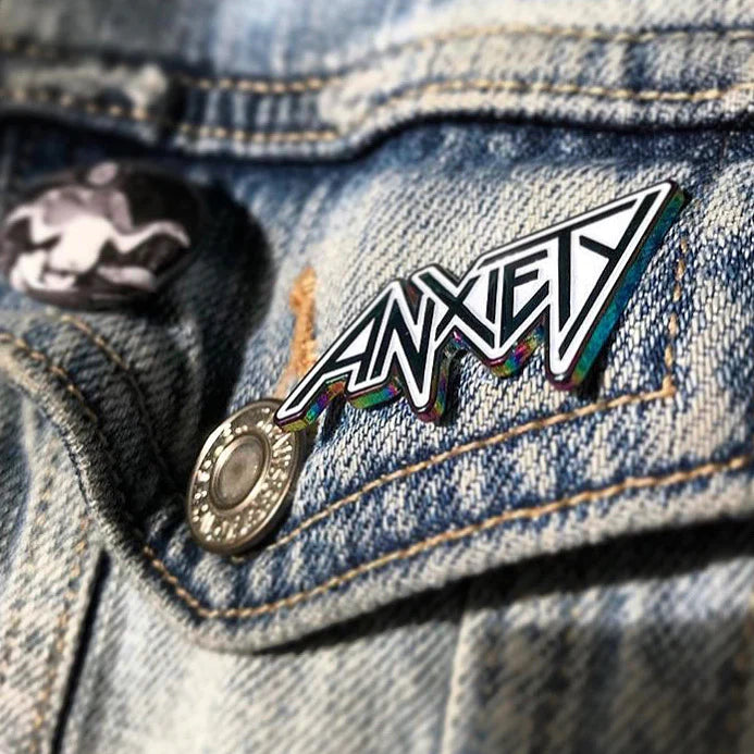Anxiety anodized enamel pin with rainbow finish on denim jacket