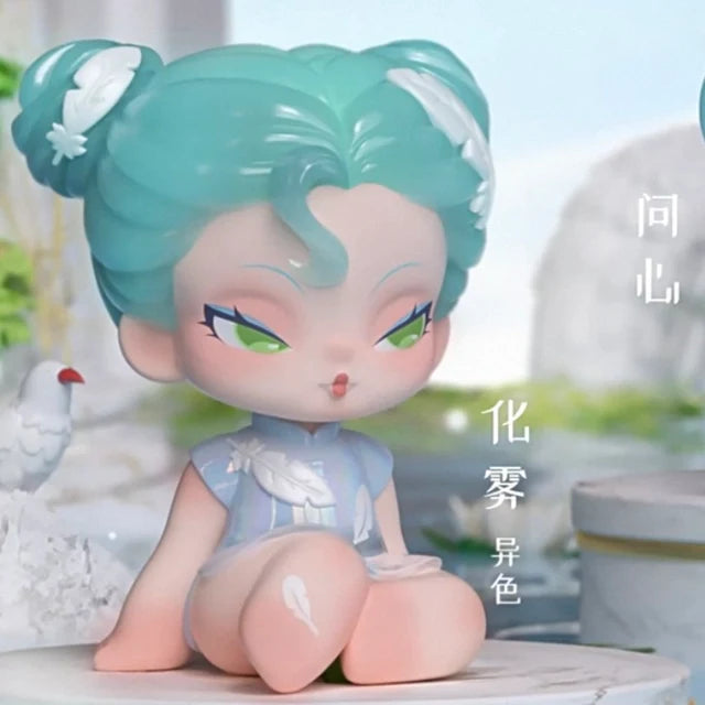DODO Nami vinyl toy with teal hair buns, wearing blue dress decorated with white feathers.