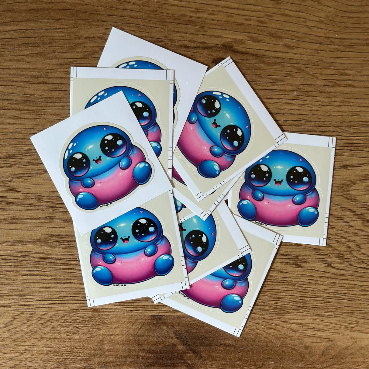 Pack of Little Fat Alien stickers from HypaHypa showing multiple vinyl stickers with the cute alien design spread out on a wooden surface.