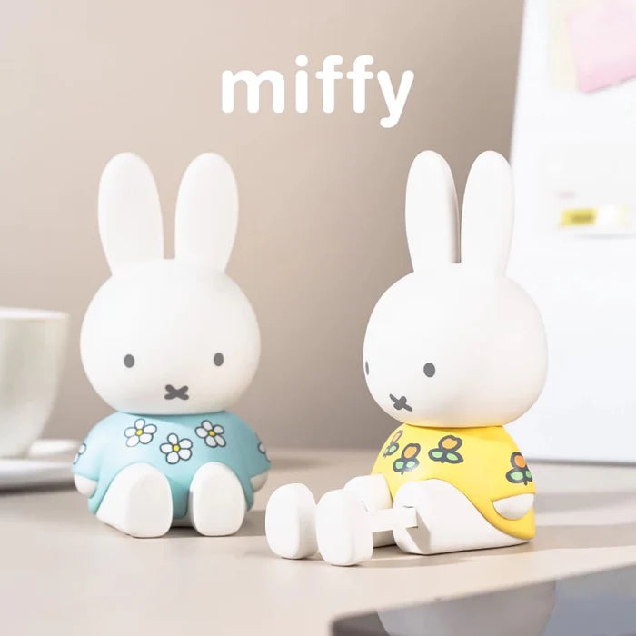 Blue and yellow floral Miffy phone stand figures displayed on a desktop