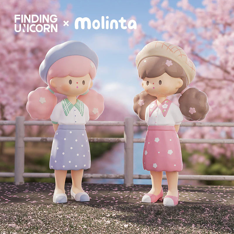 Molinta figures in pink and lavender dresses standing under cherry blossoms.