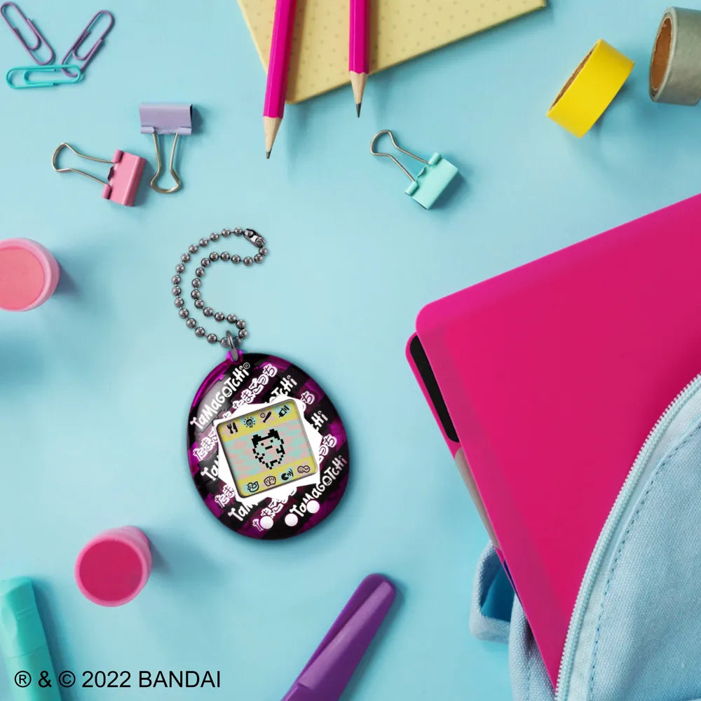 Japanese Ribbon Tamagotchi device displayed with accessories on desk.