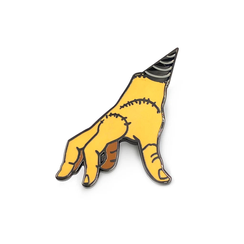 Close-up of yellow stitched horror hand enamel pin with gunmetal outline
