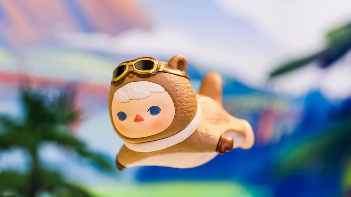 Pucky Flying Babies vinyl figure in brown bear aviator suit with flight goggles soaring in sky.