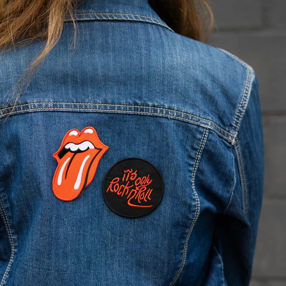 Back of a denim jacket decorated with The Rolling Stones tongue logo and circular rock ’n’ roll patch.