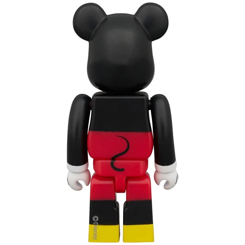 Back of Bearbrick figure styled as classic Mickey Mouse in red shorts with black body and yellow shoes.