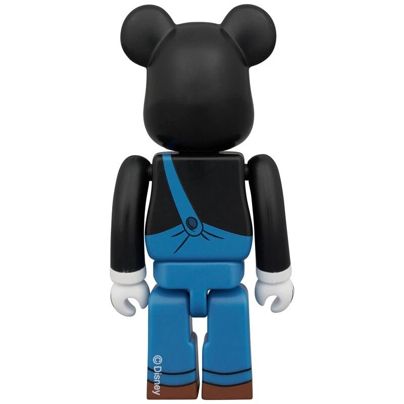 Bearbrick figure from behind dressed as Peg-Leg Pete, featuring blue overalls and black sleeves.