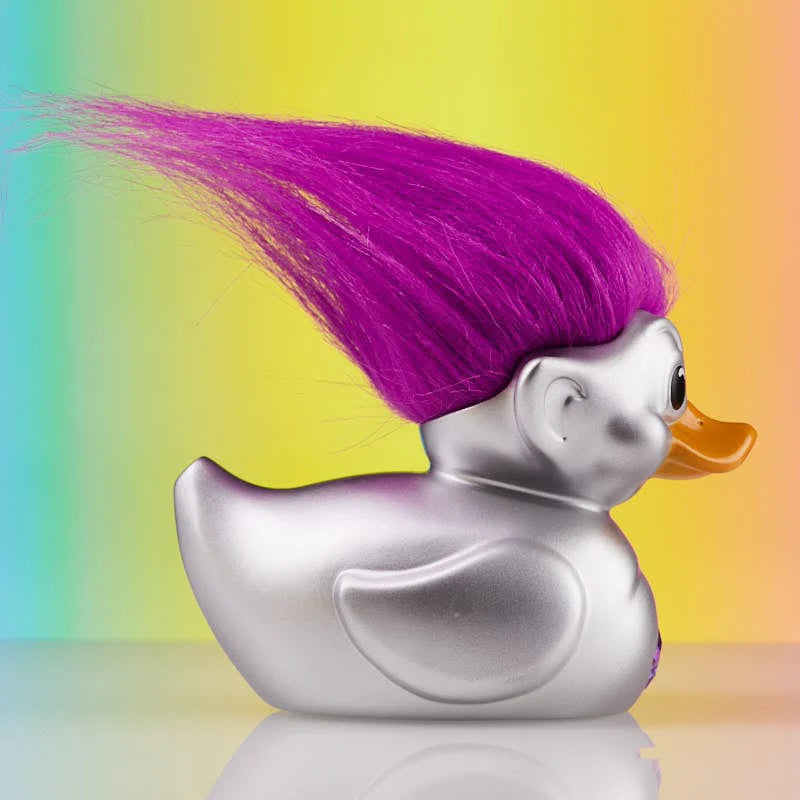 Profile view of silver collectible duck with bold purple troll hair