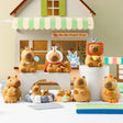 Group display of Little Bean Capybara Series figures arranged in front of a small shop backdrop.