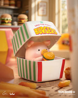 LuLu The Piggy sitting inside a burger takeout box while holding a miniature hamburger collectible figure
