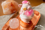 LuLu The Piggy Sakura 2 figure holding a pink sakura flower while sitting on a golden tray.