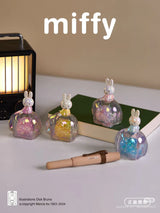 Miffy Elephant Series collectible figures displayed beside a lantern, notebook, and pen showcasing iridescent elephant designs
