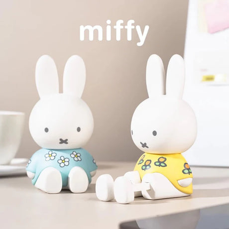 Blue and yellow floral Miffy phone stand figures displayed on a desktop