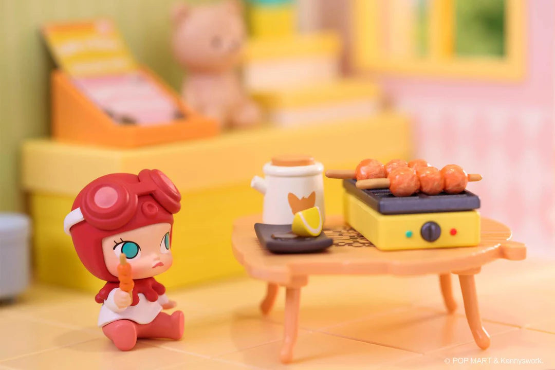 Molly figure with red hat grilling skewers on a miniature tabletop grill with side dishes