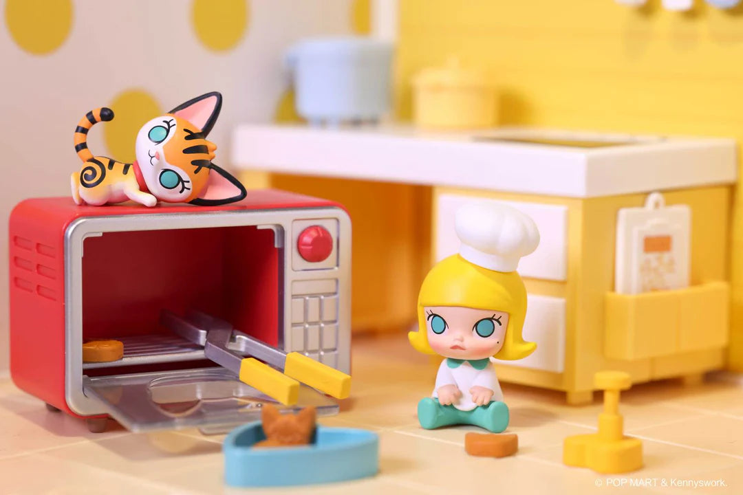 Molly figure in a chef hat sitting next to a red oven with cat figure on top, miniature kitchen props