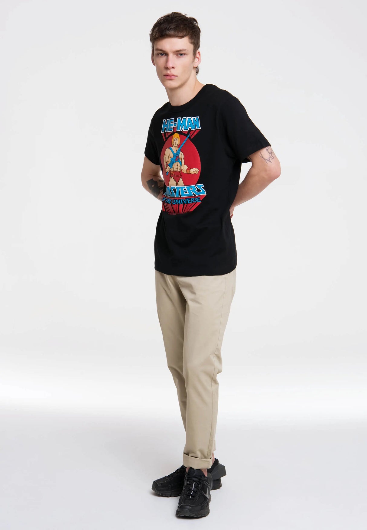 Full-body view of man styling He-Man Masters of the Universe black T-shirt with jeans