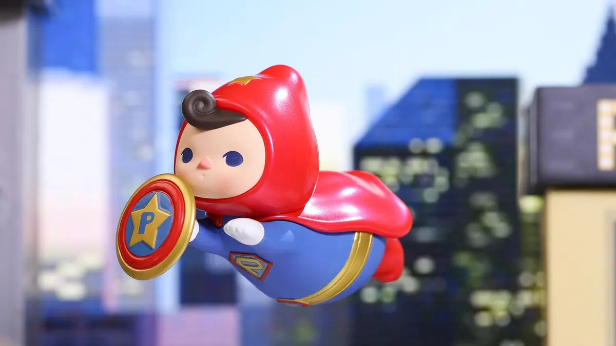 Pucky Flying Babies vinyl figure Superpower Pino with red cape and shield flying through city scene.