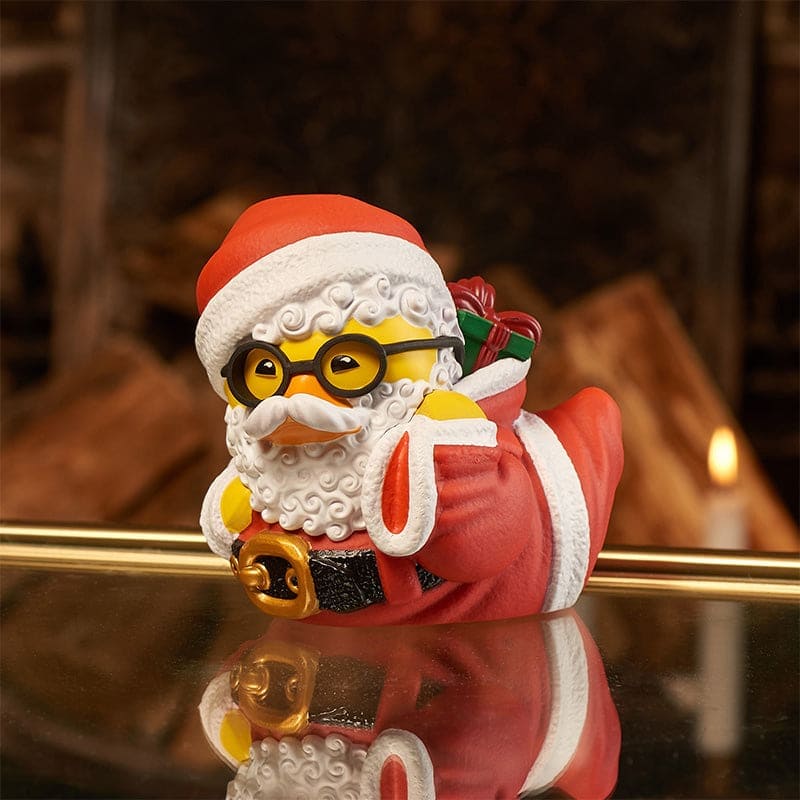 Santa Claus TUBBZ duck figure leaning on one arm with fireplace background.