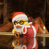 Santa Claus TUBBZ duck figure leaning on one arm with fireplace background.