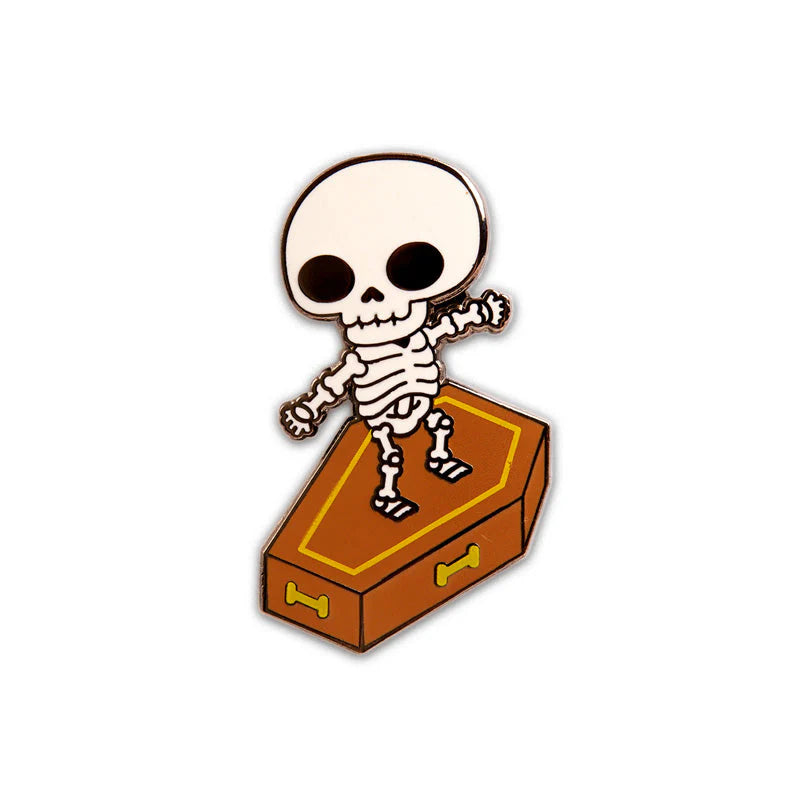 Skull Surfer enamel pin close-up showing skeleton surfing a coffin with black nickel plating