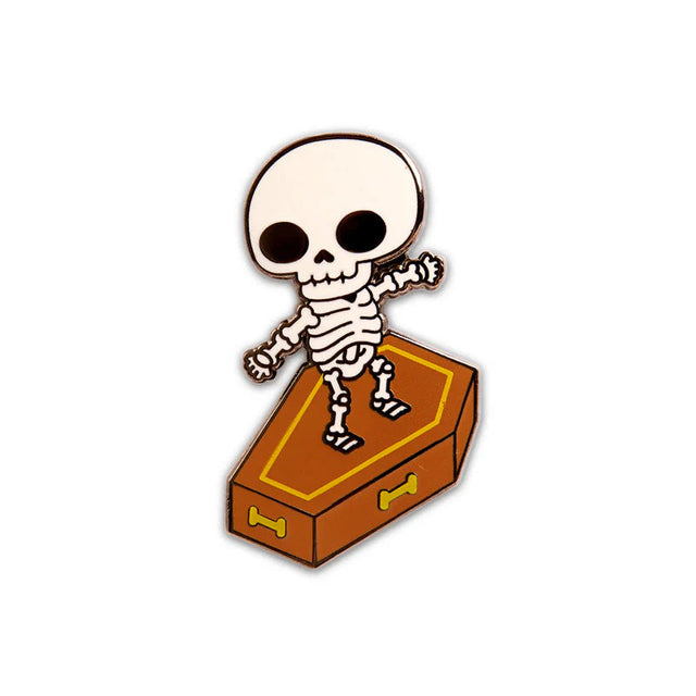 Skull Surfer enamel pin close-up showing skeleton surfing a coffin with black nickel plating