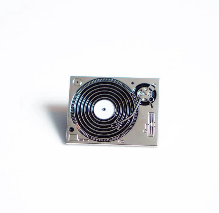 Close-up of turntable enamel pin with metallic finish