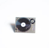 Close-up of turntable enamel pin with metallic finish