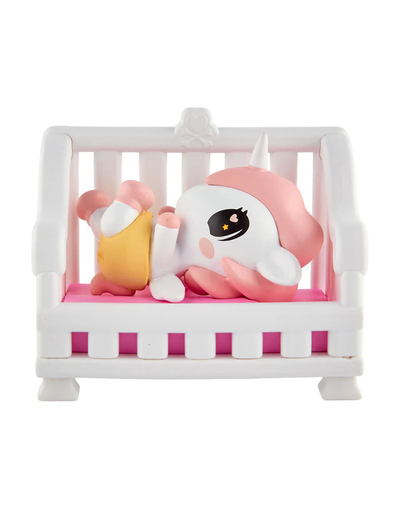tokidoki Baby Unicorno Cuddles figure lying in pink baby crib