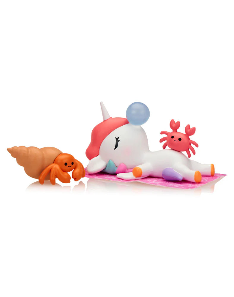 Fun in the Sun Unicorno figure napping on beach towel with crabs