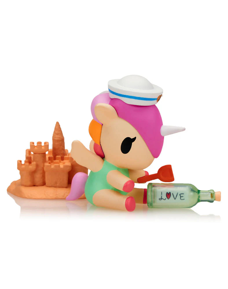Fun in the Sun Unicorno figure building sandcastle with message in a bottle