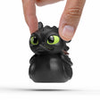 Hand holding Toothless Mini TUBBZ figure showing small size and detailed sculpt.