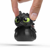 Hand holding Toothless Mini TUBBZ figure showing small size and detailed sculpt.