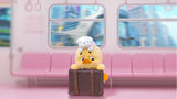 Upset Duck travel mood vinyl figure sitting on pink subway seat with suitcase