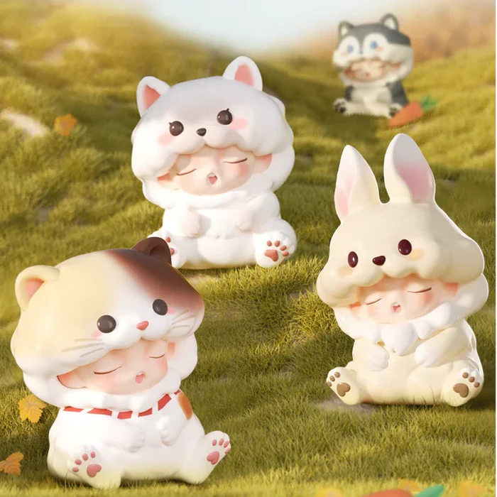 White cat, calico cat, and beige bunny Yumo figures sitting on grassy field.