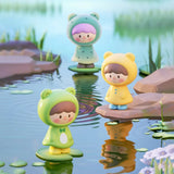 Frog-themed UliUli collectible figures standing on lily pads beside a peaceful pond